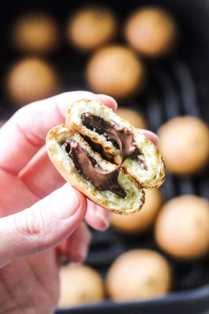 holding stuffed pancake bite with chocolate cooked in air fryer