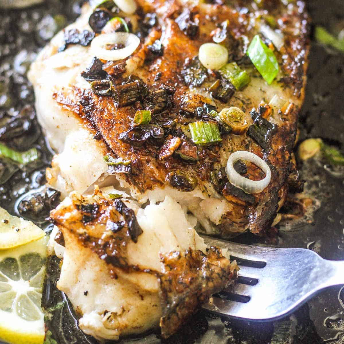 buttery tilefish recipe with lemon and chopped green onions with a fork