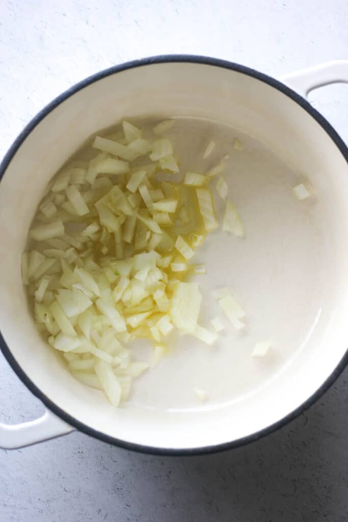 chopped onion in a heavy white pot with oil