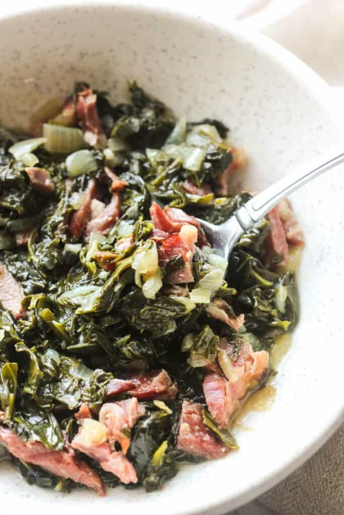 cooked turnip greens with ham hock on the serving white plate