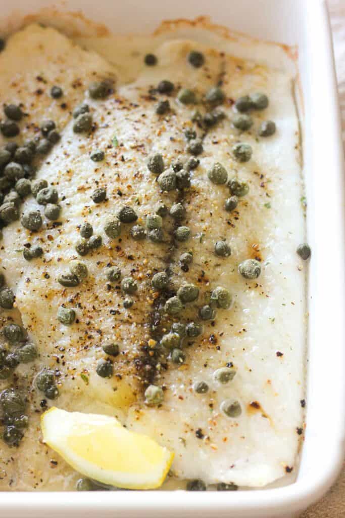 baked white fish in the baking dish with lemon
