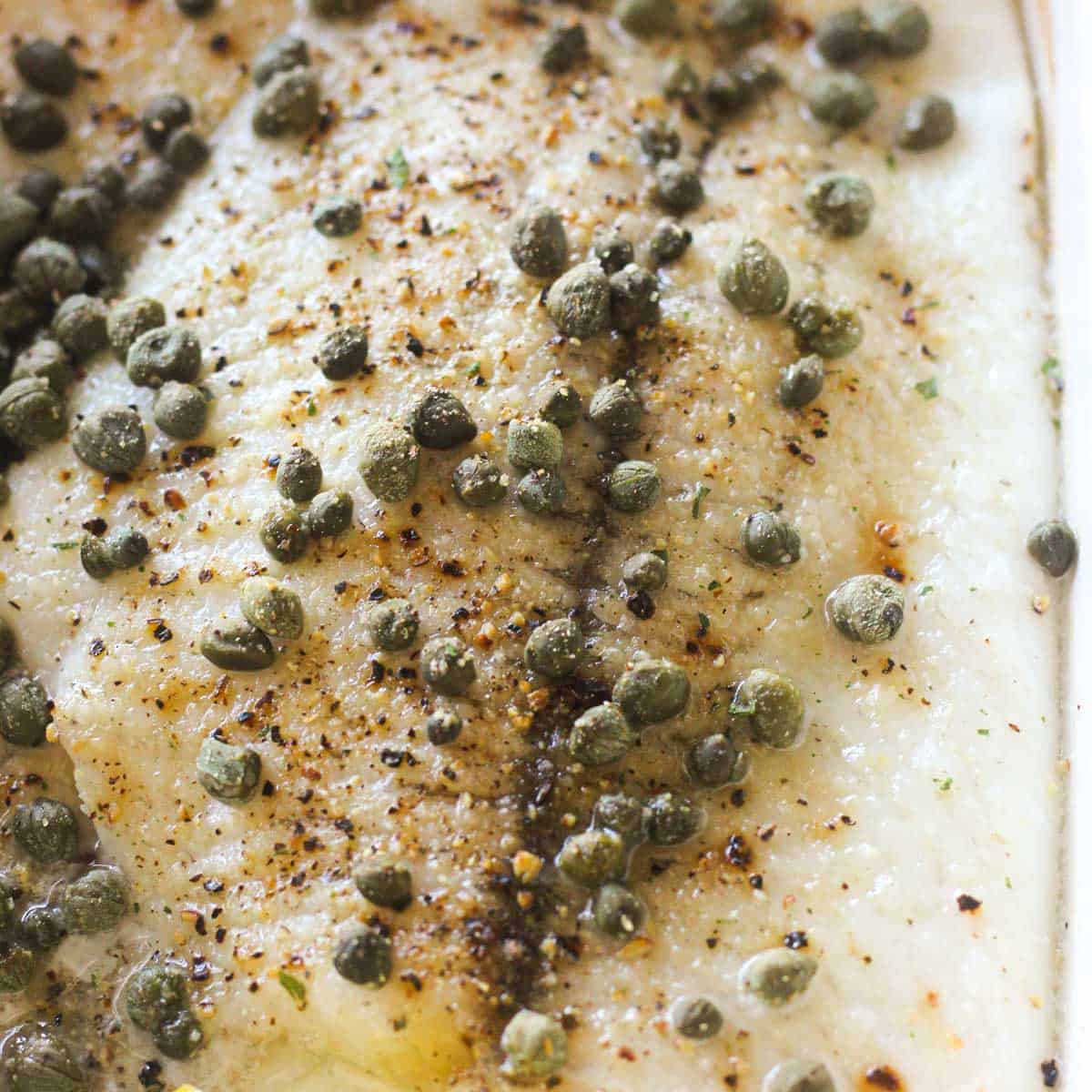 oven cooked plaice with capers on top, black peppers and lemon