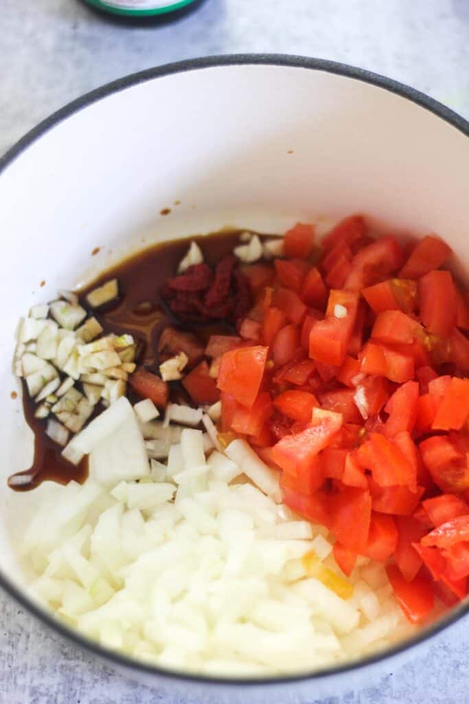 chopped onion, tomatoes, garlic with soy saucew and tomato paste in the bowl before cooking