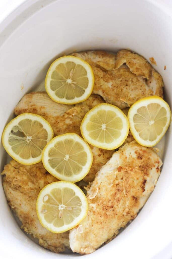 fried chicken breast with lemon slices in slow cooker