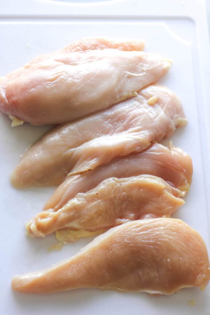 raw chicken breasts on the white cutiing board