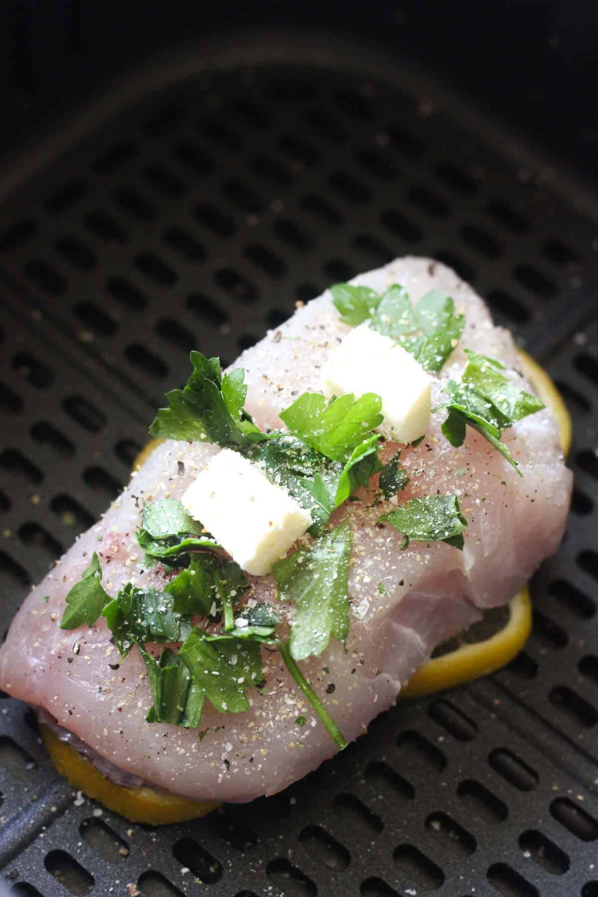 seasoned grouper in air fryer with parsley and lemon on top