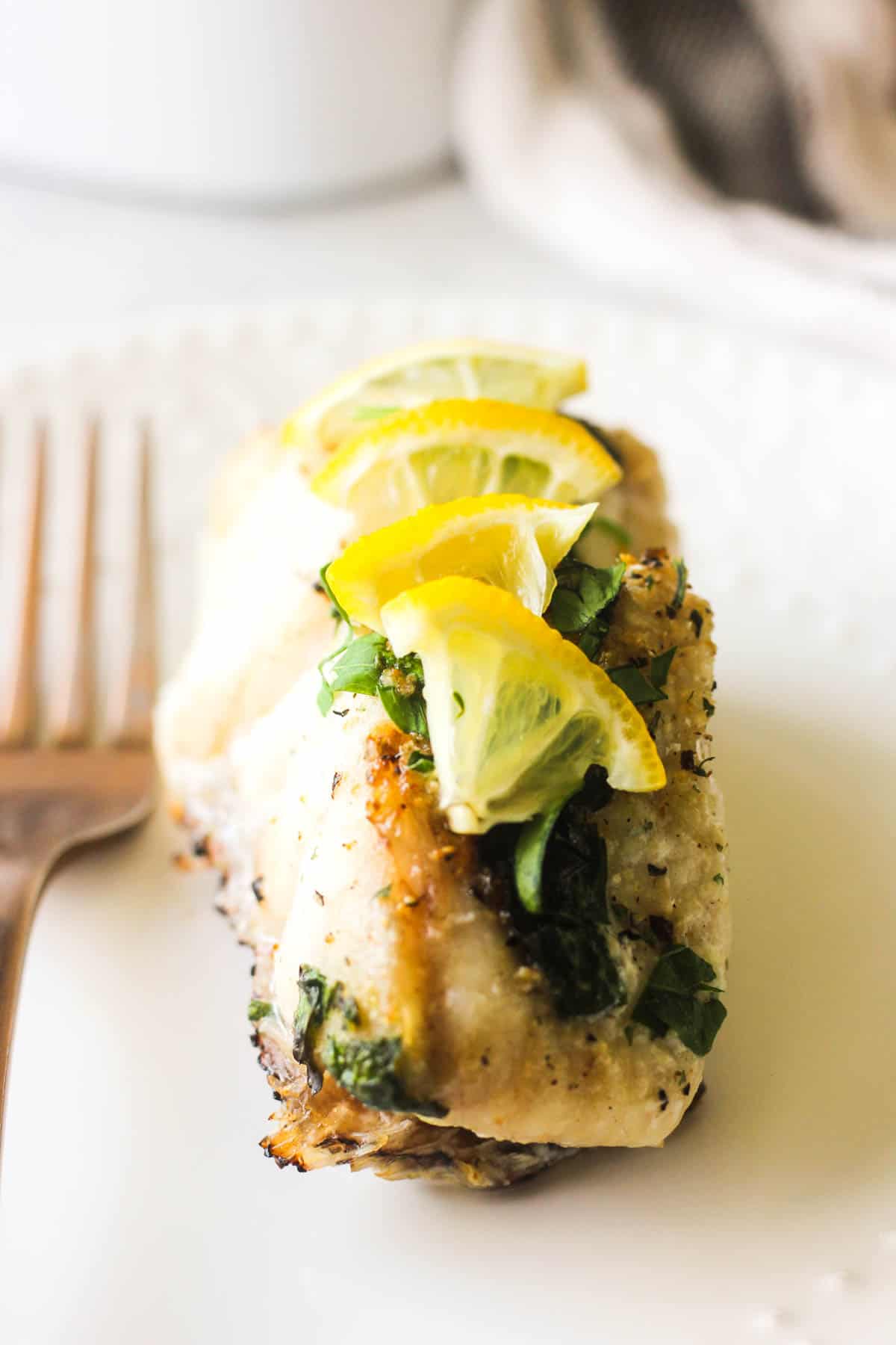 white fish fillet on a white plate with lemons and parsley