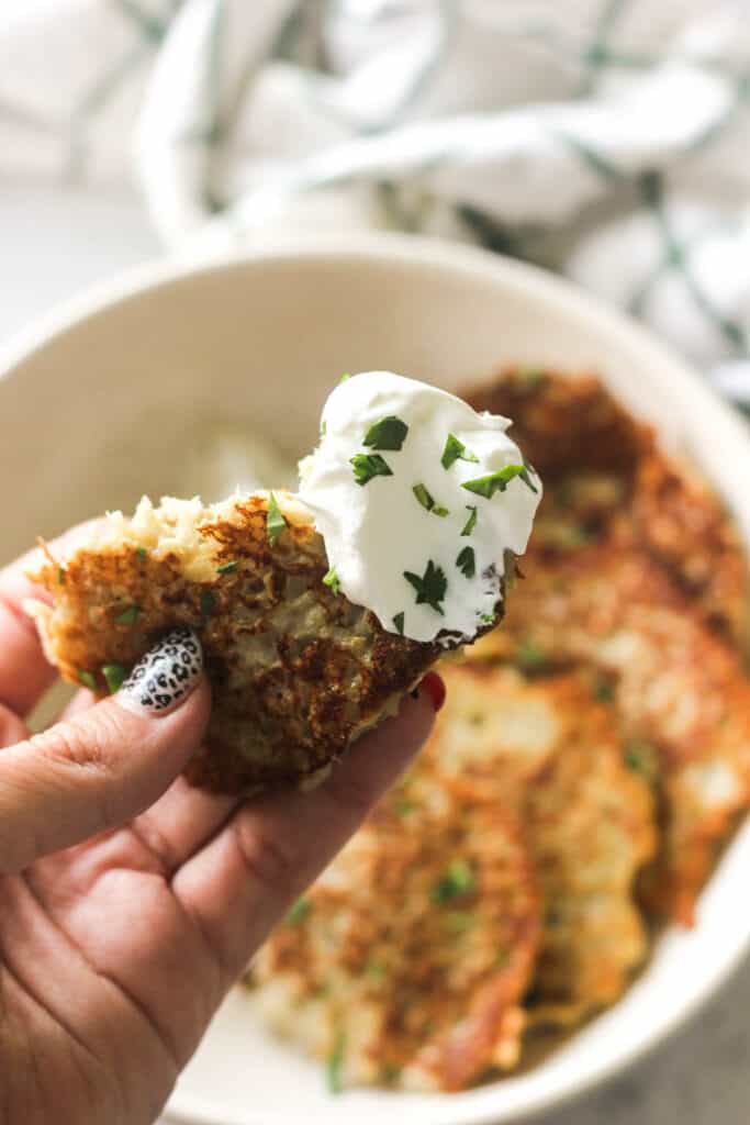 holding a piece of eggplant pancake with sour cream in the hand