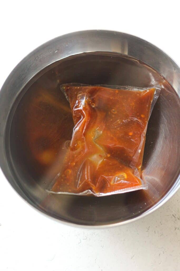 a plastic package with sauce in the bowl full of hot water
