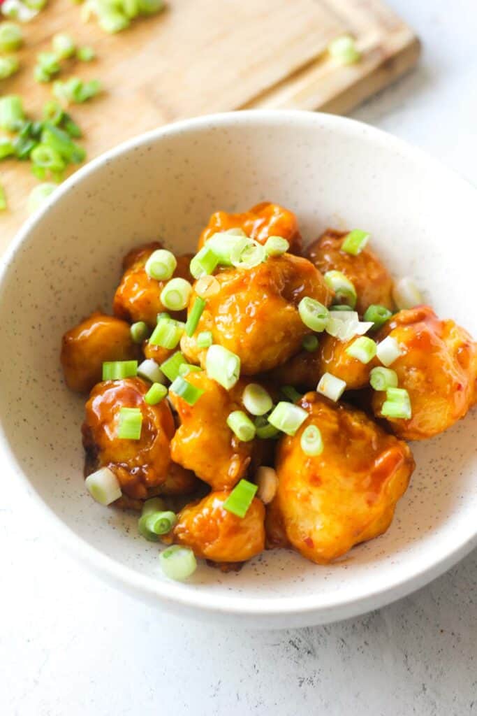 trader joe's kung pao cauliflower cooked in air fryer in the bowl with chopped green onions on top