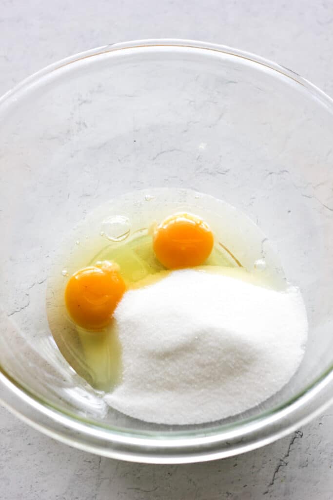 two eggs and sugar in the glass bowl