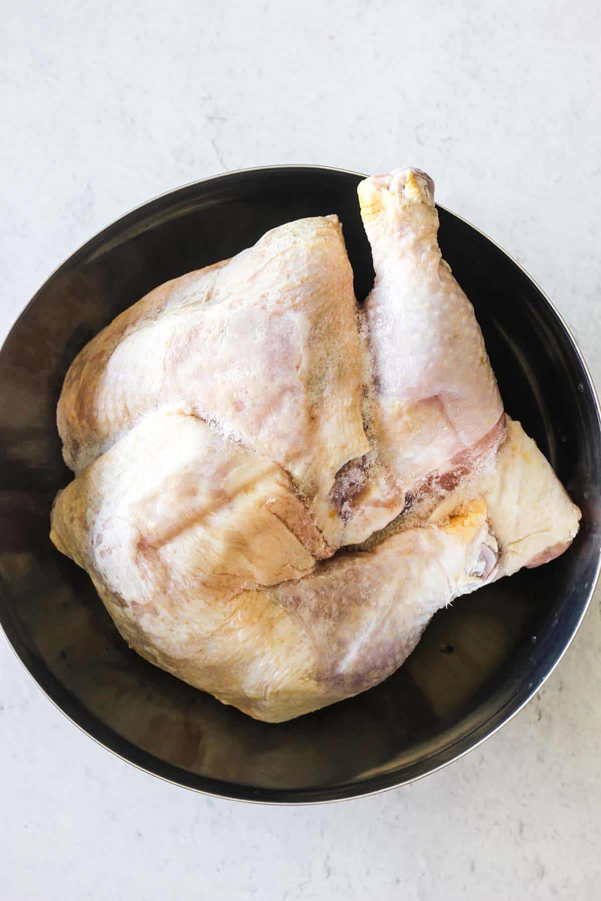raw chicken legs in a large metal bowl