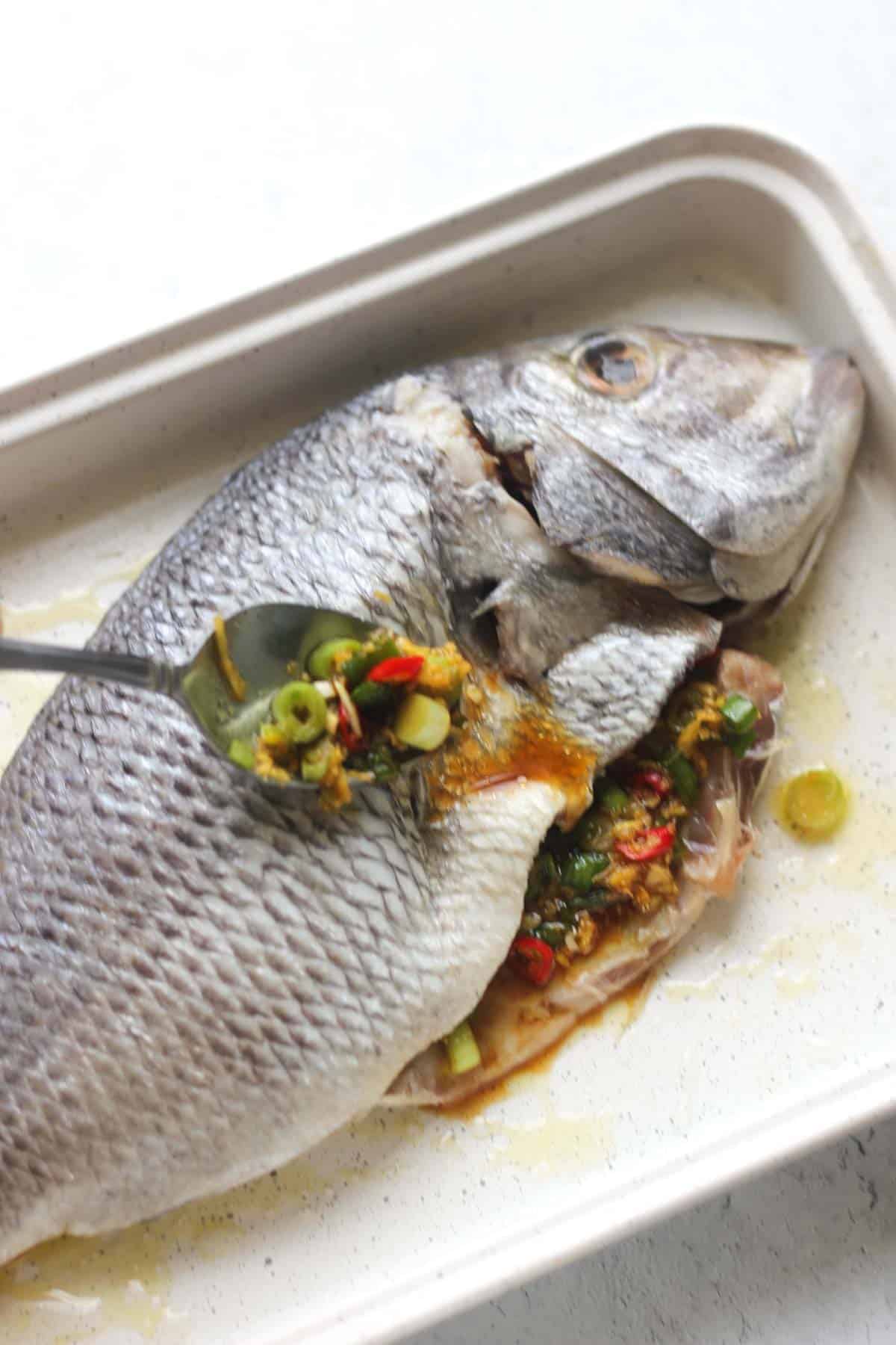 covering whole white fish with spice mix