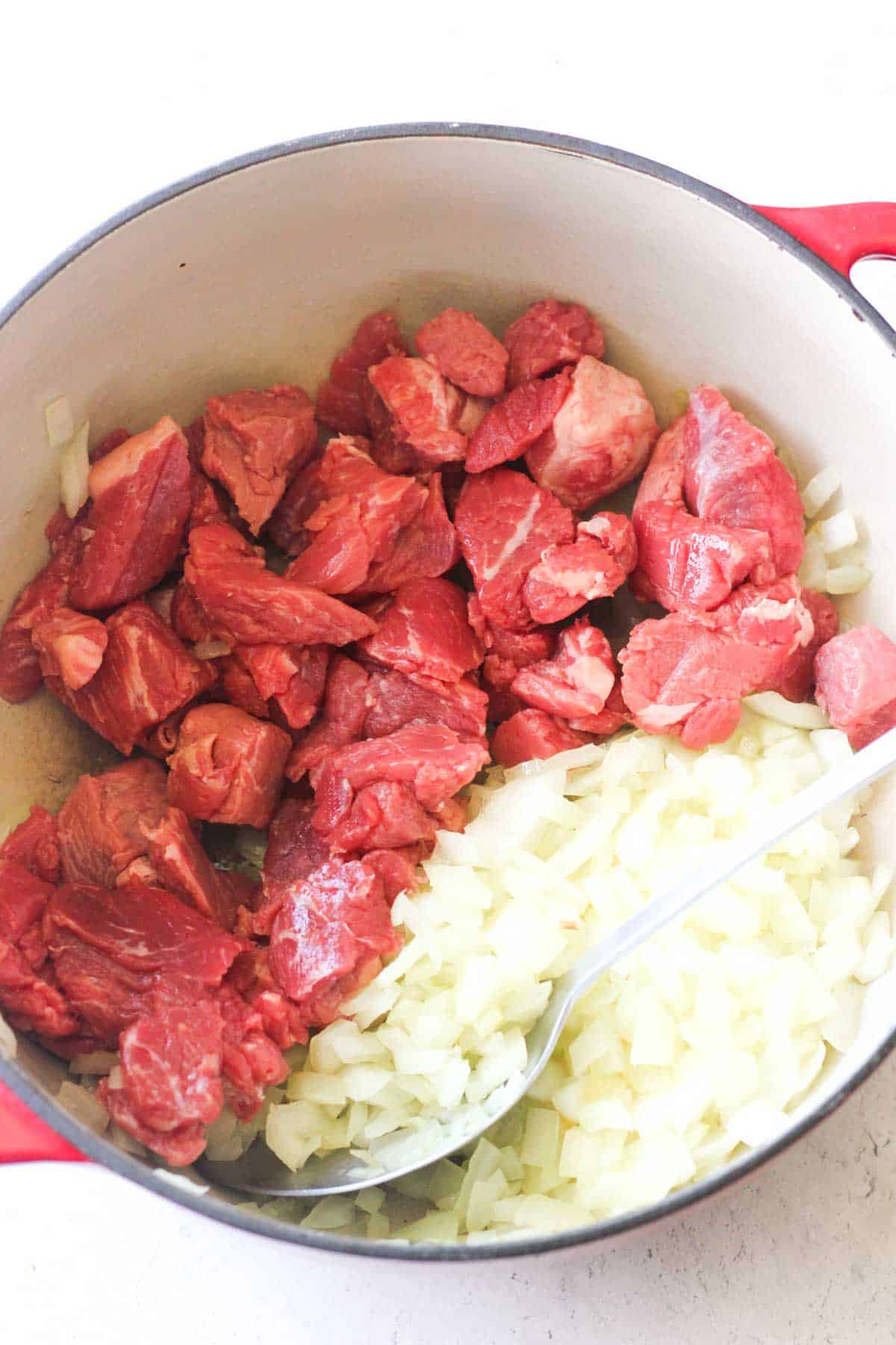 stew meat and chopped onions in the pot to make slovak goulash