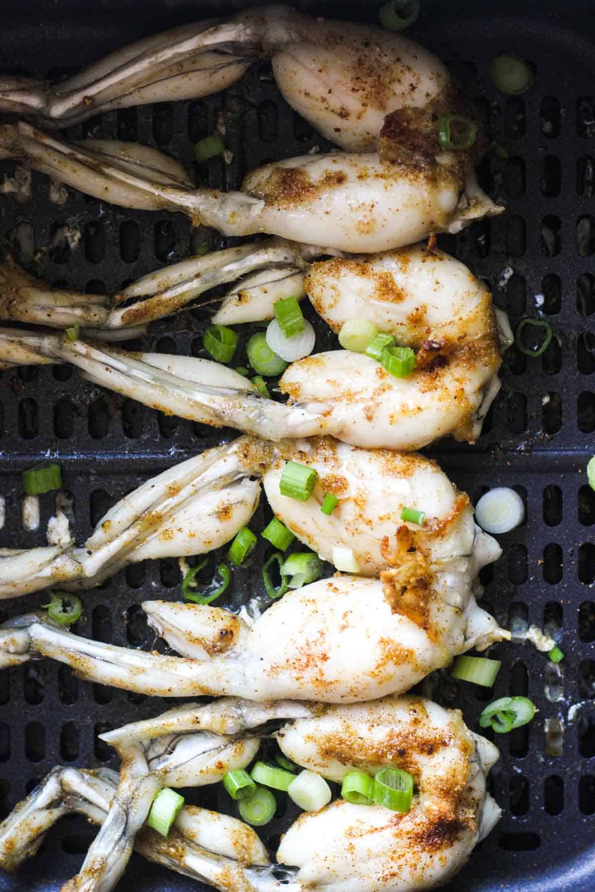 chopped green onions covering frog legs