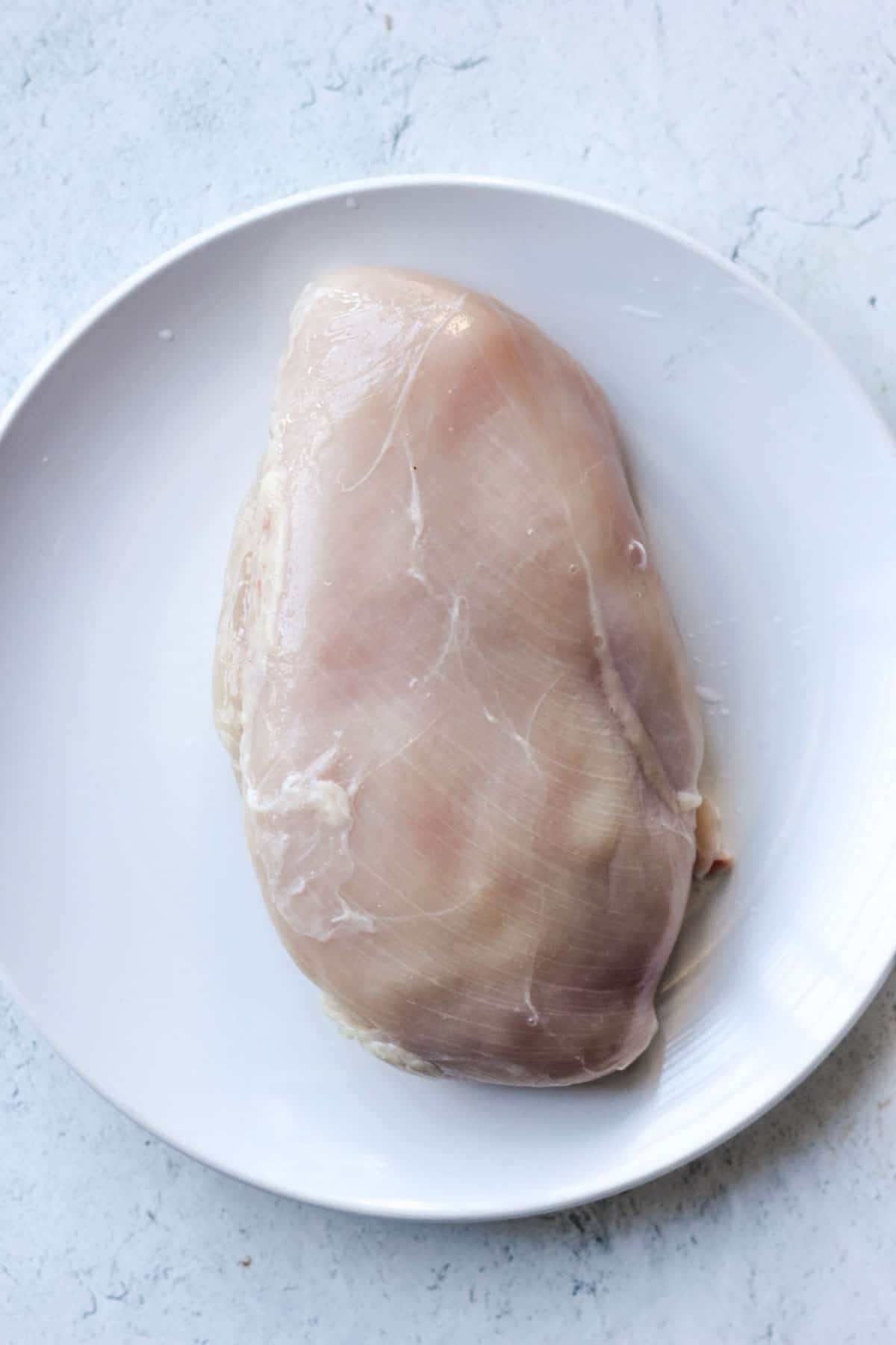 raw chicken breast on the white plate
