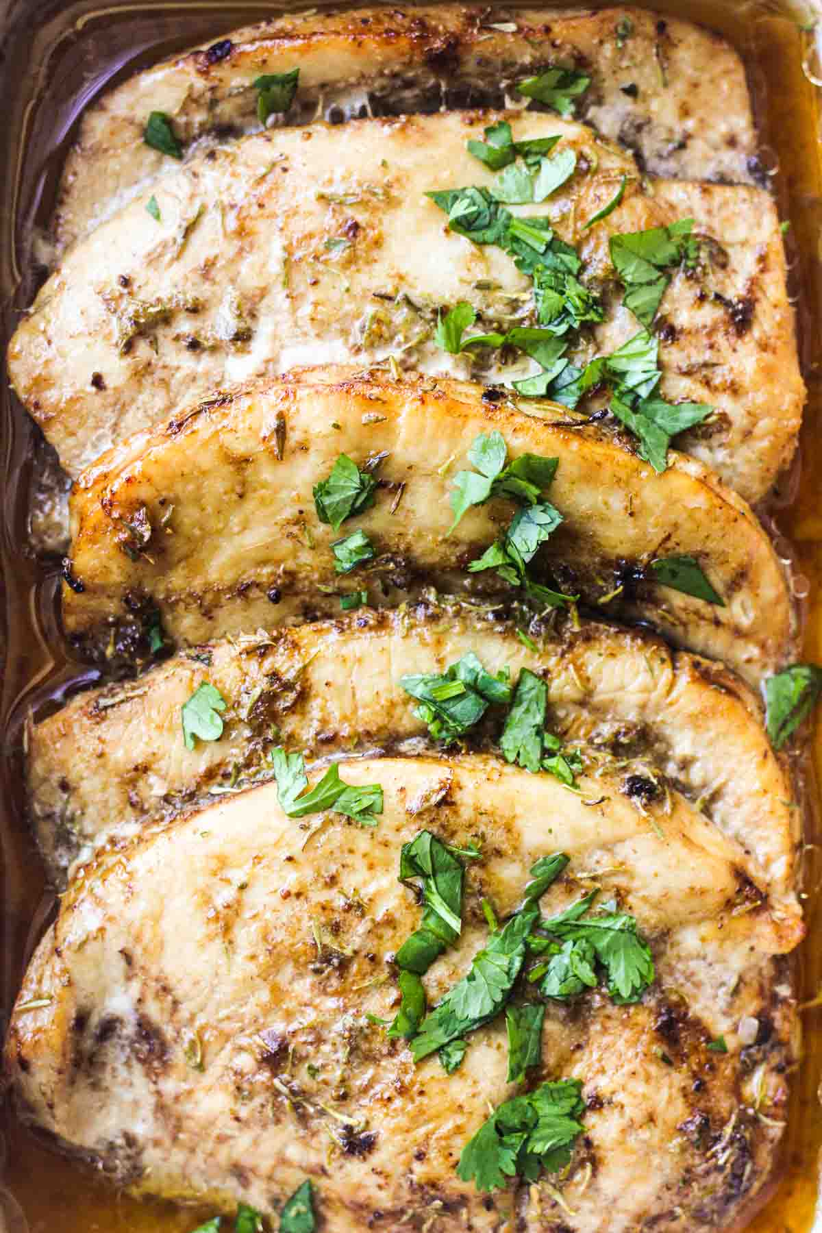 baked turkey steaks in the baking dish with chopped cilantro on top
