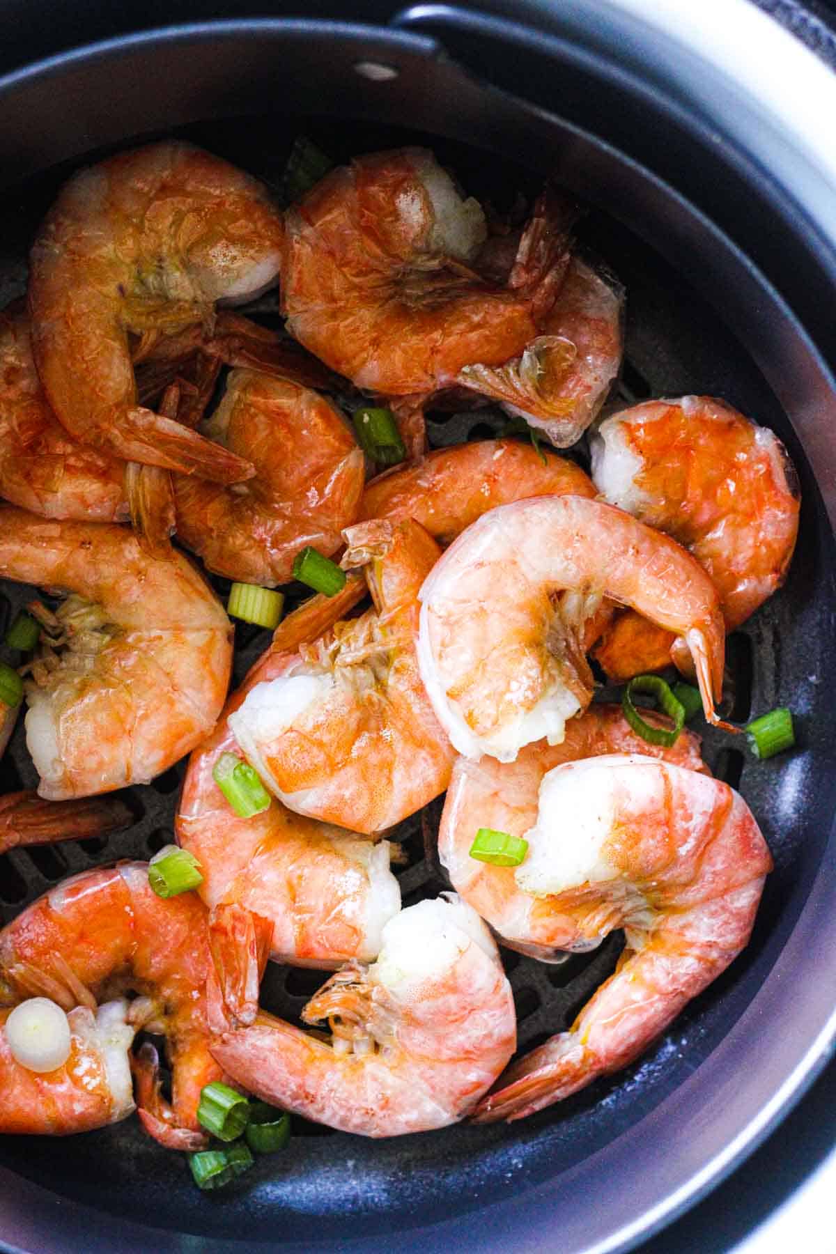 chopped green onions on top of steamed shrimp in ninja foodi basket