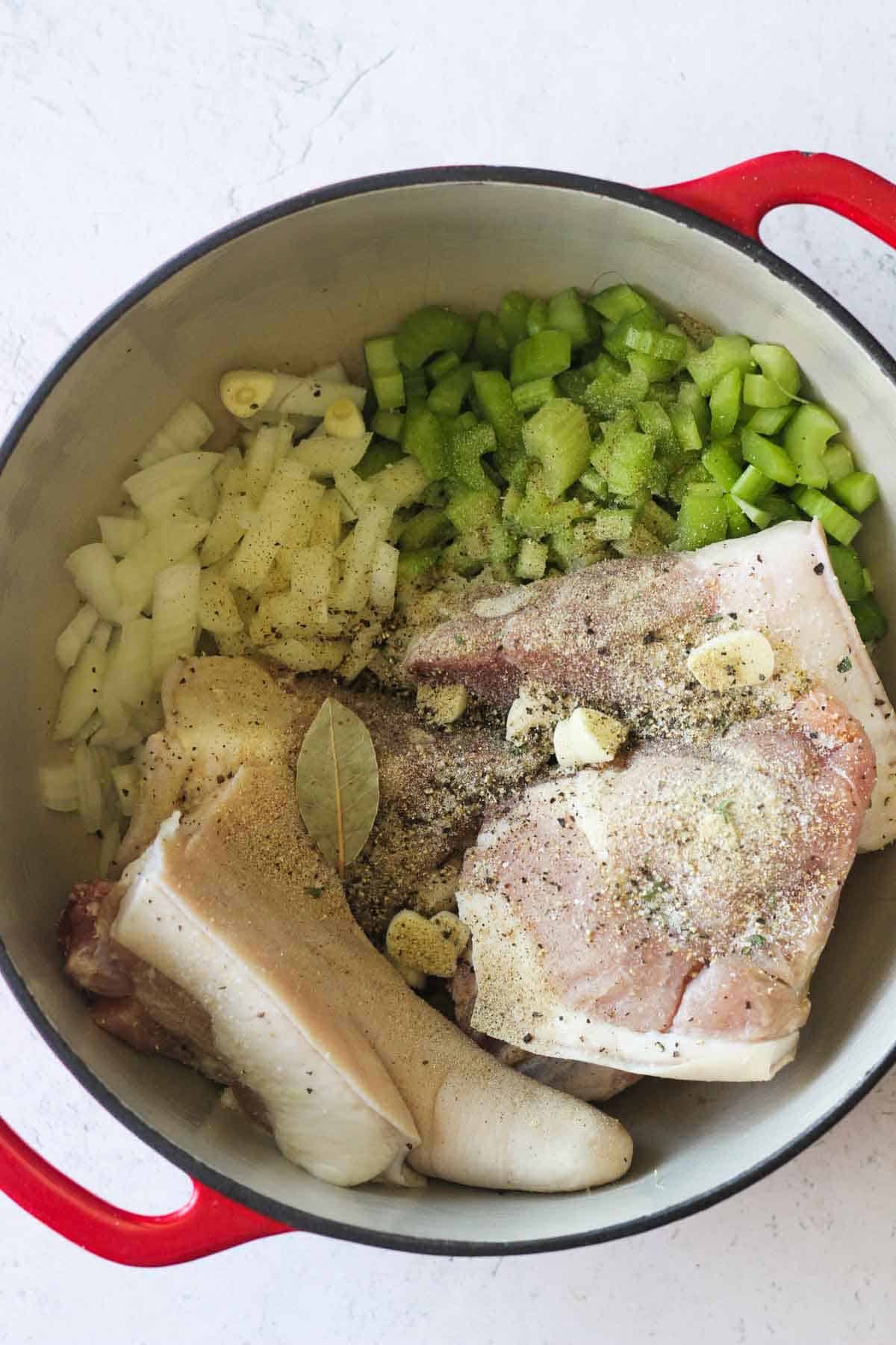 raw seasoned pig tails in the pot with vegetables