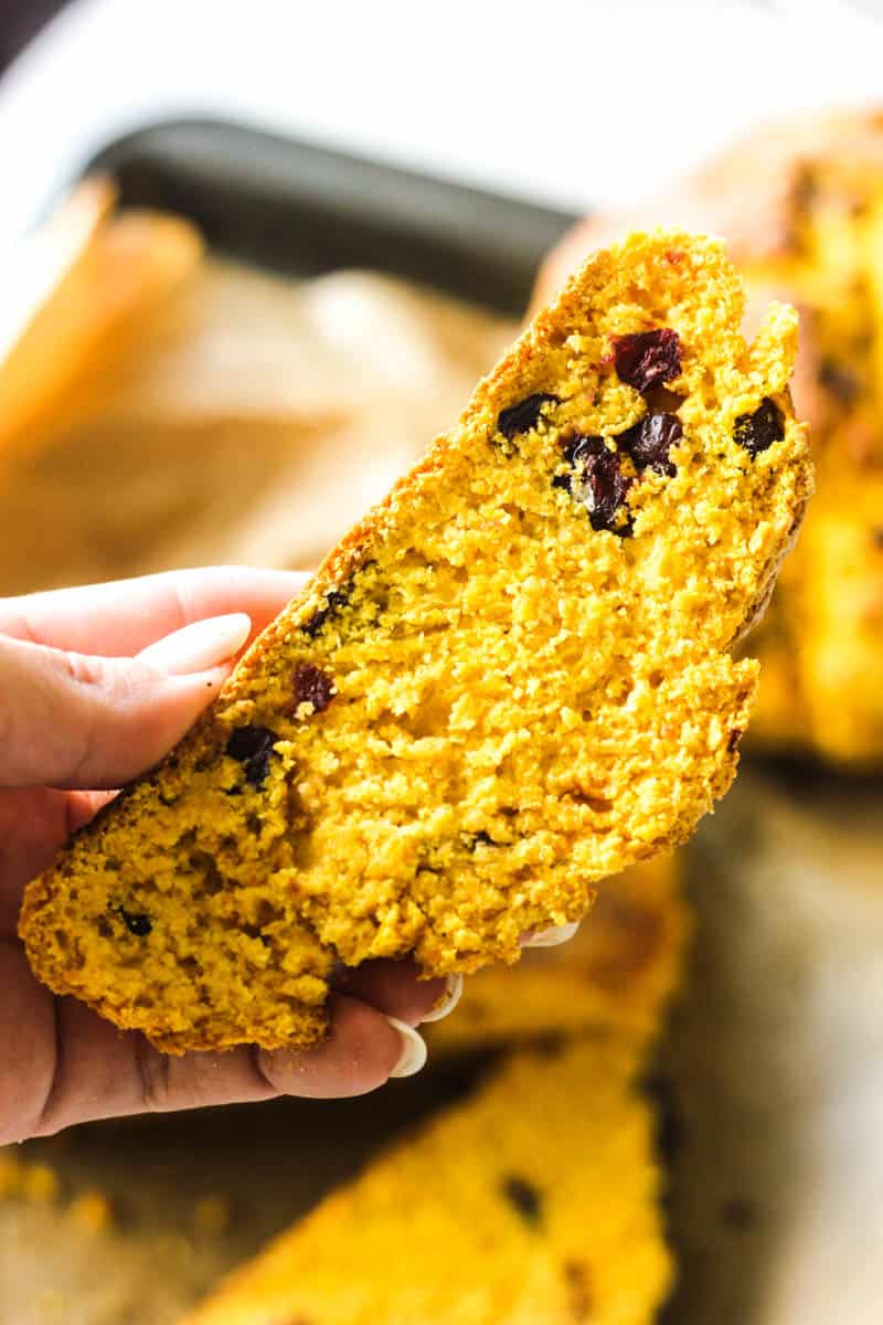 a piece of pumpkin soda bread with craberries in hand