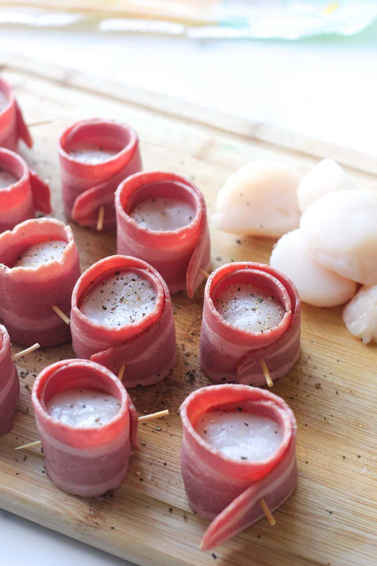 raw turkey bacon wrapped sea scallops on the cutting board