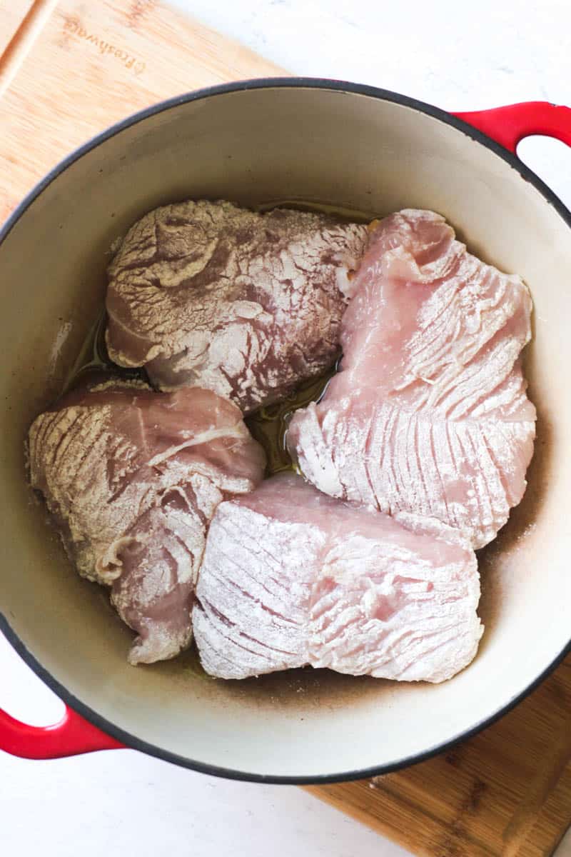 searing turkey tenderloi pieces covered in flour in the heavy pot