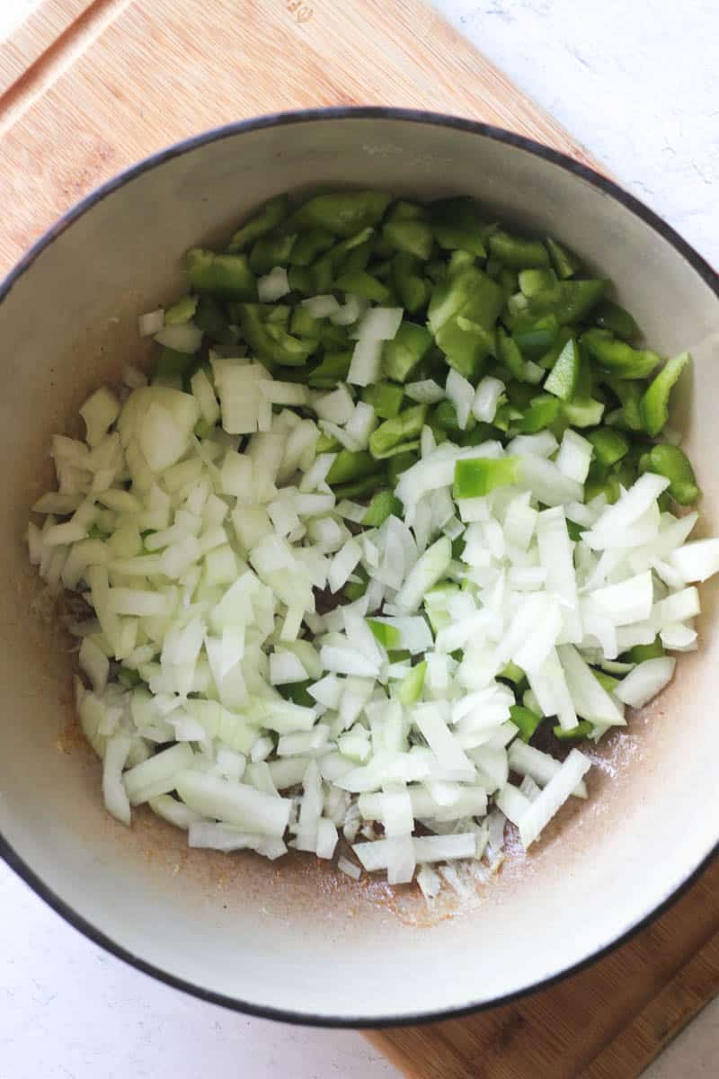 chopped green bell peppers and onions in the pot