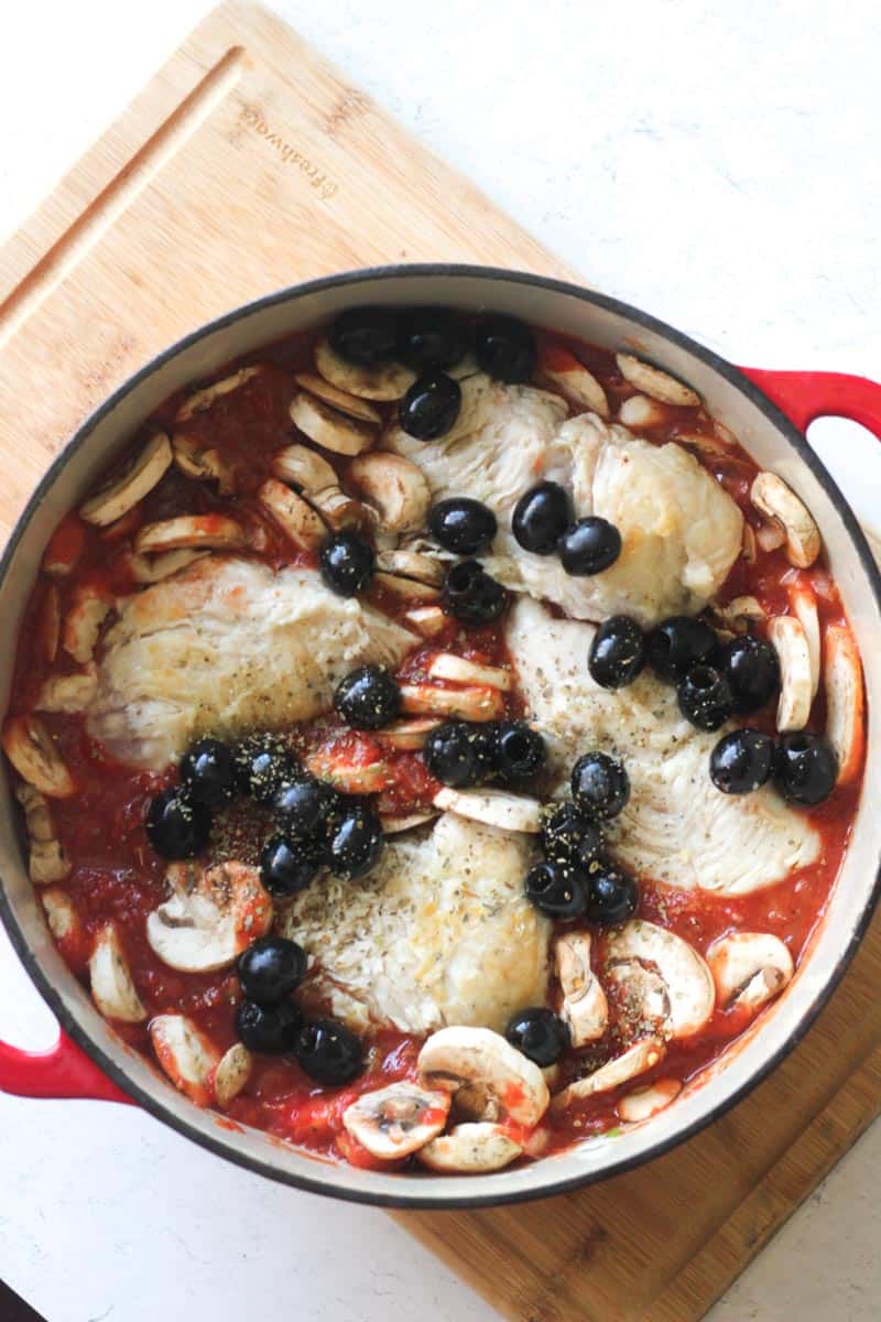 turkey with olives, mushrooms in red tomato sauce in the red pot