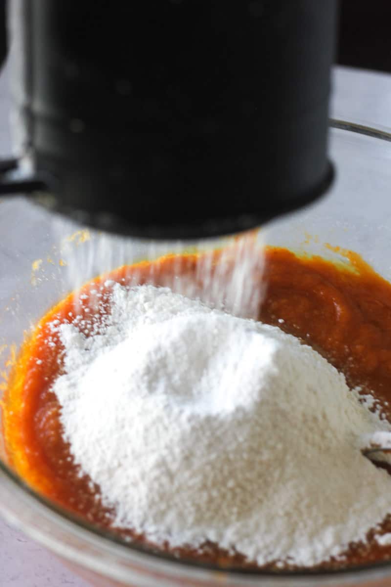 sifting flour into the pumpkin bread batter