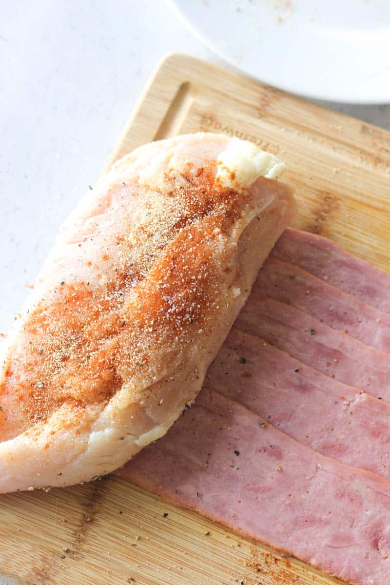 wrapping chicken in bacon on a cutting board