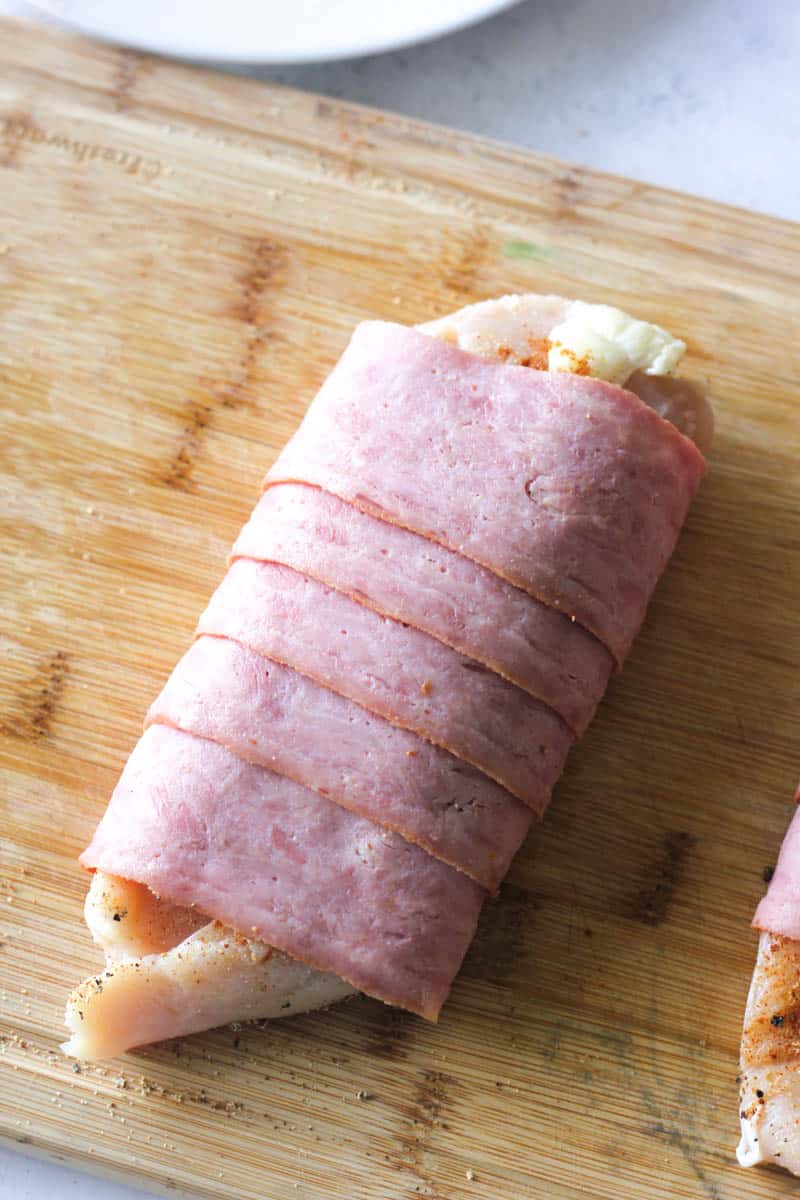 raw chicken breast covered in turkey bacon