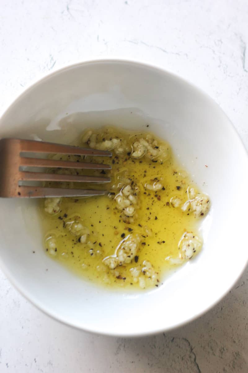 mixing oil with garlic in a small bowl