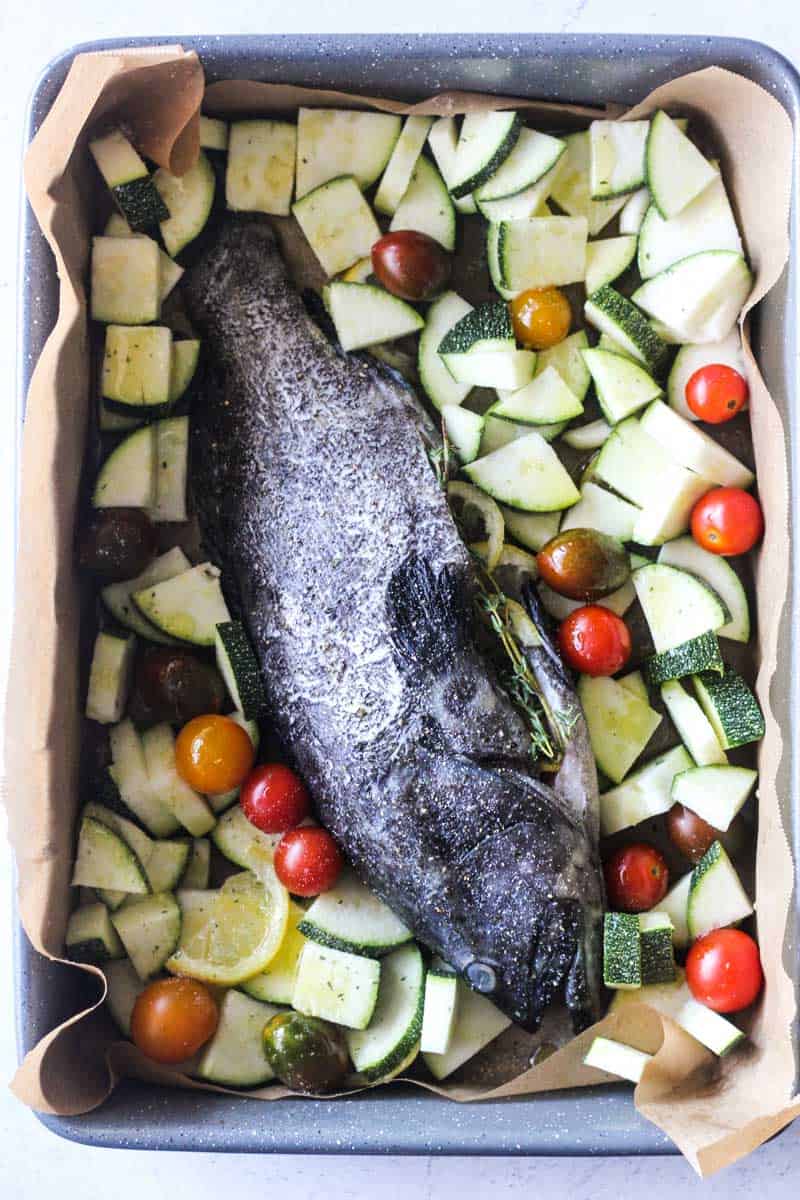 raw whole fish with vegetables in the baking dish
