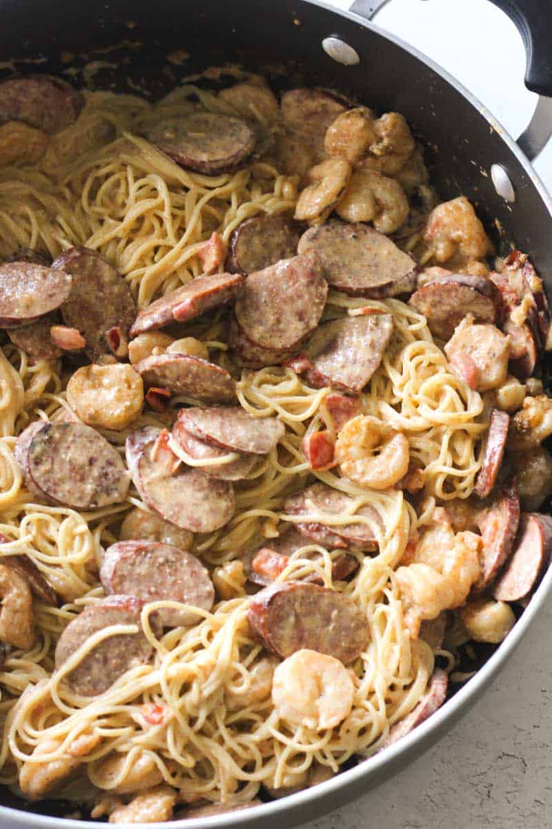 creamy cajun angel hair pasta with sausage and shrimp in the pan