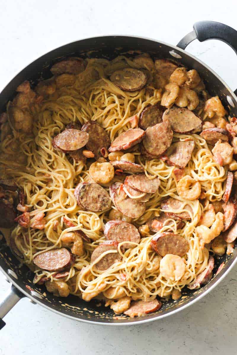 creamy cajun angel hair pasta with sausage and shrimp in the pan