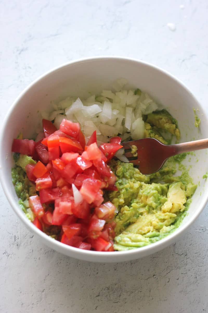 chopped tomatoes, white onions and avocado in a bowl