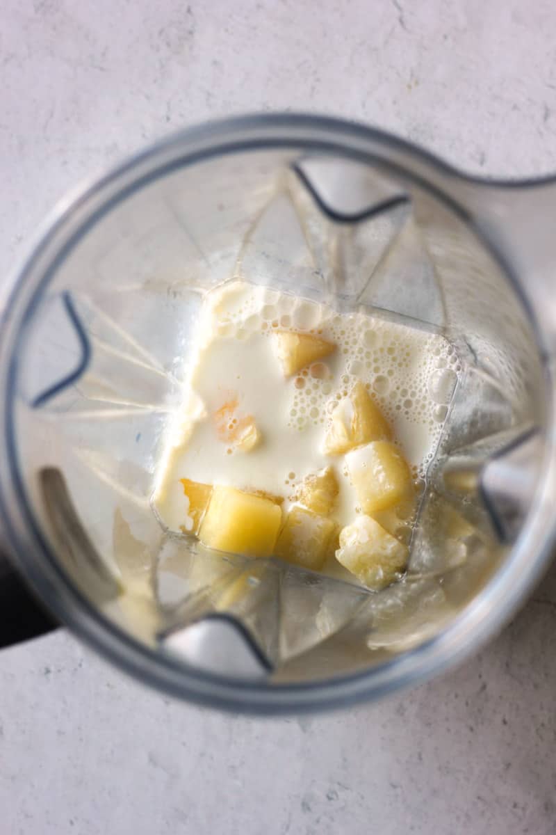 adding milk to pineapple chunks in the blender