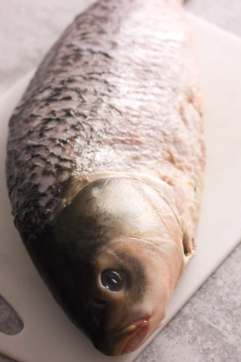 raw whole fish on the white cutting board