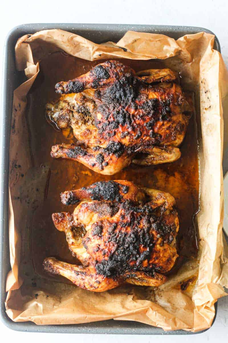 two baked cornish hens on a parchment paper with crispy skin