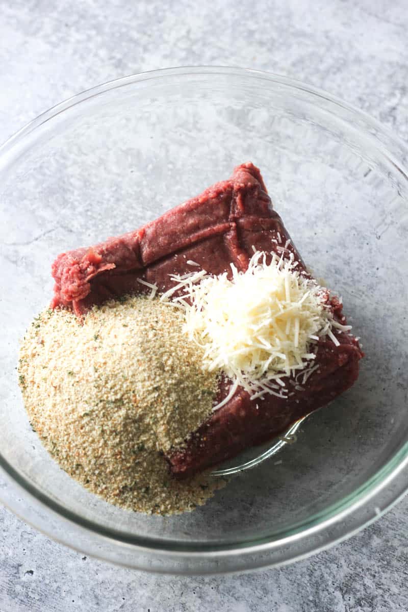 parmesan cheese, breadcrumbs and meat in the glass bowl