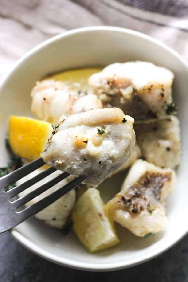 cooked white fish pieces in a bowl with lemon