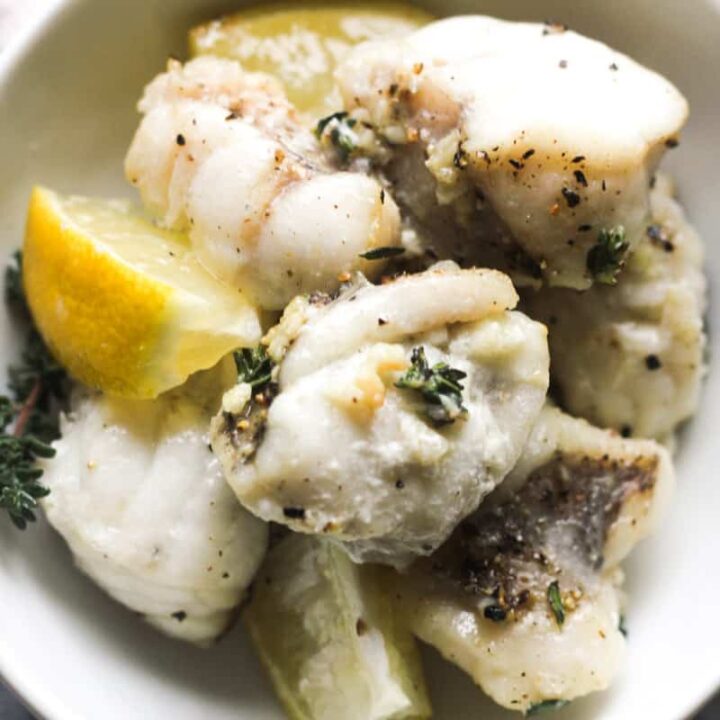 air fryer monkfish bites in a bowl with lemon wedges and seasonings
