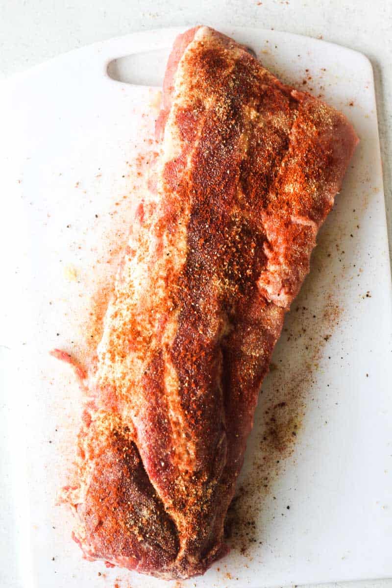 raw pork ribs with seasoning on white cutting board