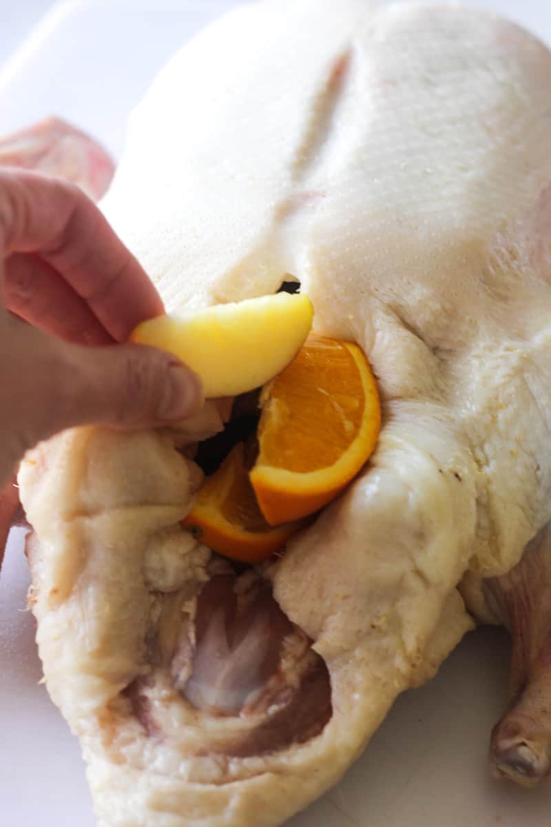 adding oranges and apple slices to the duck
