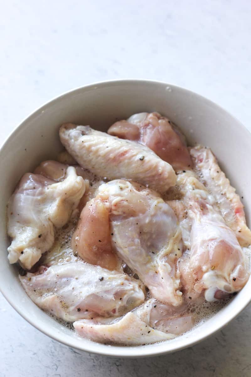 raw chicken wings maritaning in an egg and pepper mixture