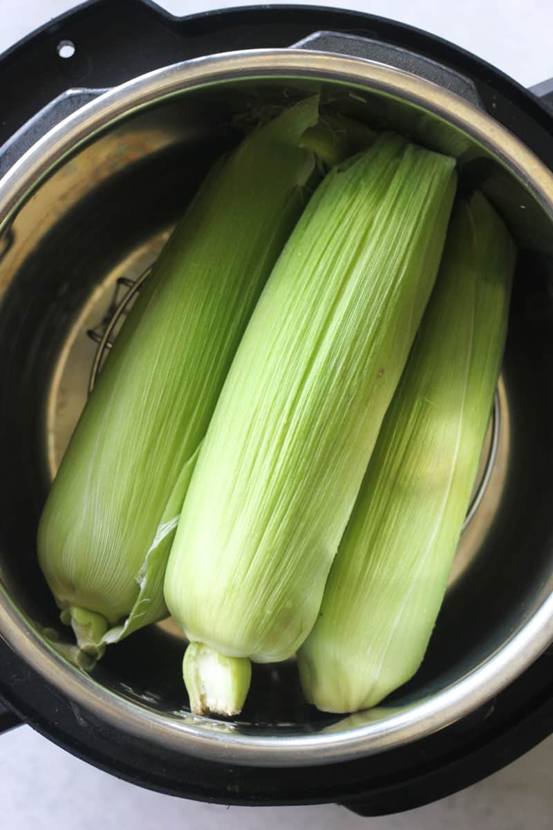 three ears of corn in the pressure cooker pot