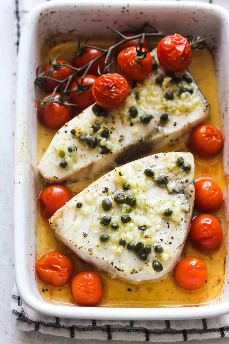 top view of baked white fish with tomatoes and capers
