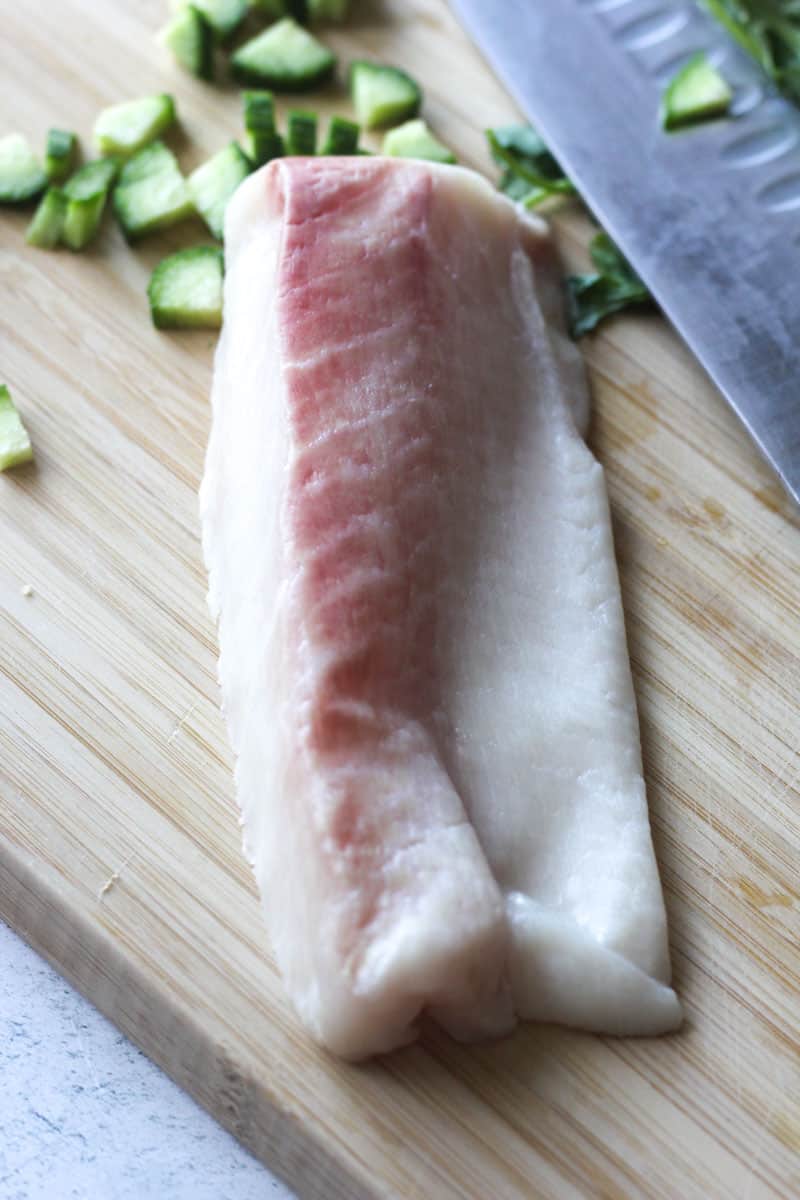 a piece of raw fish on the cutting board