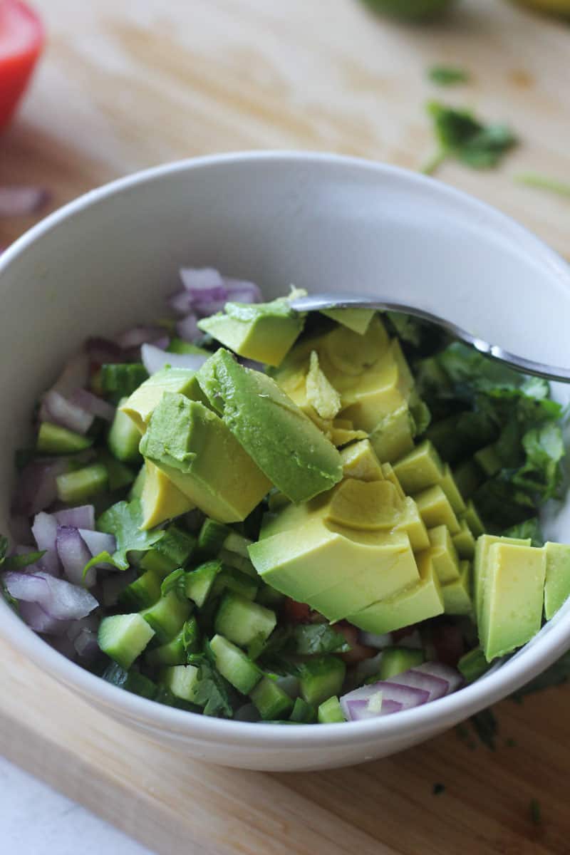 diced avocados on top of chopped onions and cucumbers