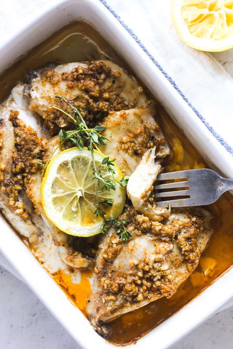 baked grouper cheeks with lemon slices and fork with a piece on it